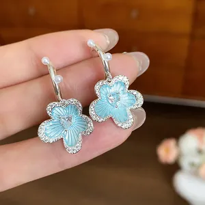 Detail shot of light blue flower earrings featuring white pearls and heart-shaped zircon