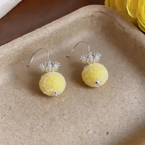 Detailed macro view of yellow round pendant earrings with silver crown decorative tops