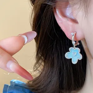 Macro detail view of silver-tone flower hoop earrings with blue enamel and pearls