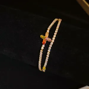 Gros plan sur un bracelet plaqué or à double rangée avec un charm de fleur en zircons