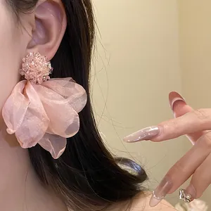 Detail of peach chiffon flower earrings with beaded center and silver needle.
