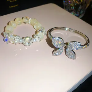 Close-up of sparkly zircon butterfly bangle and elegant beaded bracelet set for women.