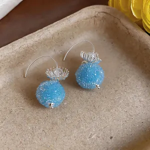 Macro view of blue glass flower textured round drop earrings on tray