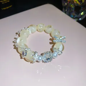 Elegant beaded bracelet featuring sparkling zircon charms and pearls on a soft pink surface