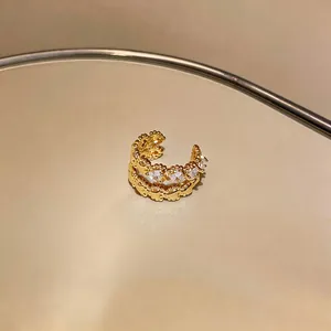 Close-up of elegant gold-plated ear cuff featuring sparkling zircon heart pattern.