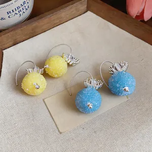 Detailed view of yellow and blue textured glass ball pendant earrings on fabric