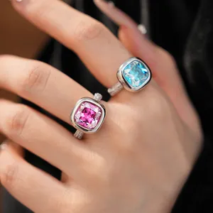 Dettaglio ravvicinato di anelli di lusso in zircone quadrato rosa e blu su una mano