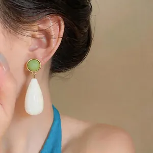 Detailed view of minimalist resin teardrop earring with green and white elements.