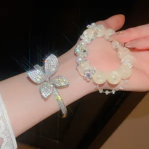 Detailed view of sparkling zircon butterfly bangle and pearl-like beaded bracelet set