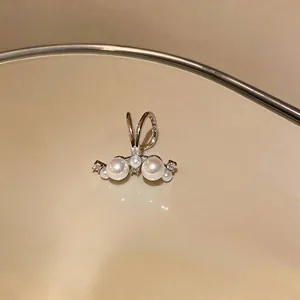 Close-up view of silver-tone ear cuff featuring lustrous pearls and sparkling zircons