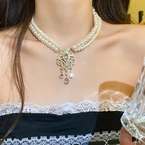 Dettaglio collana di perle multistrato con ciondolo a fiore di strass stile vintage