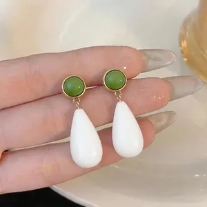 Close-up of minimalist resin teardrop earrings in green and white tones