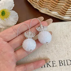 Detail shot of elegant glass flower drop earrings with a frosted white round bead