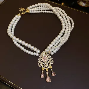 Dettaglio della collana di perle multistrato con ciondolo a fiore di strass e cristalli rosa.