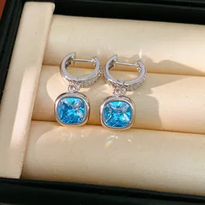 Dettaglio ravvicinato di orecchini argentati con zirconi blu brillanti taglio cushion