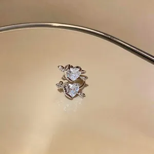 Close-up of sparkling heart zirconia ear cuffs with Cupid's arrow design in silver