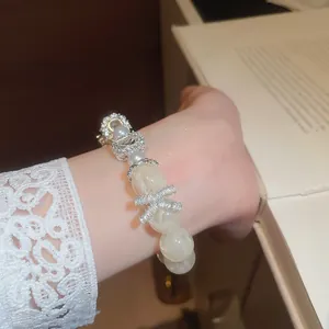 Close-up detail of a sparkling zircon bracelet with pearls and elegant white lace cuff
