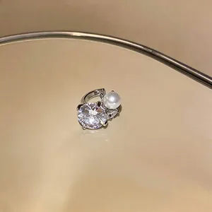 Detailed view of silver ear cuff featuring a sparkling zircon and a white pearl.