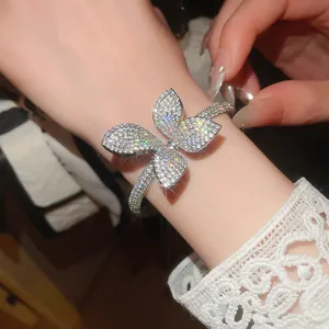 Detail shot of sparkling zircon flower bangle on wrist with elegant lace sleeve.