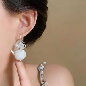 Detailed close-up of an elegant glass flower and white textured ball dangle earring