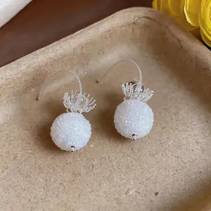 Detail shot showing elegant white frosted glass ball pendant earrings with silver hooks