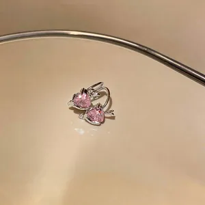 Detailed macro view of sparkling pink heart zircon ear clips with a polished silver finish