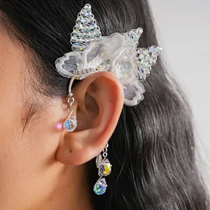 Vista dettagliata di un elegante ear cuff a farfalla in pizzo bianco con perline lucide.