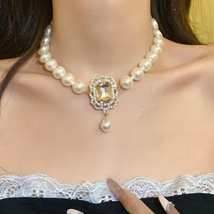 Primo piano di una collana di perle vintage con ciondolo in gemma champagne e strass.