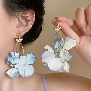 Close-up detail of Korean style blue fabric flower earrings with gold bird charm