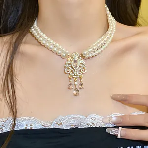 Dettaglio di una collana di perle multistrato vintage con ciondolo floreale a strass.