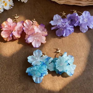 Detailed close-up of handmade fabric flower drop earrings in vibrant colors on wood
