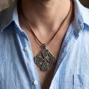 Detail view of a vintage Celtic cross pendant worn on a brown leather cord.