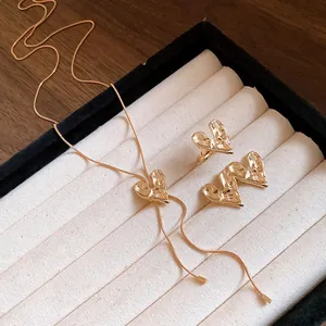Detailed view of minimalist gold metal heart jewelry set with necklace and earrings