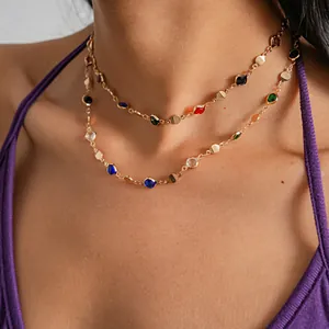 Detail shot of a multi-colored crystal necklace with gold geometric disks on a model.