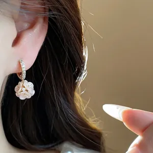 Close-up of elegant zircon flower drop earrings with pearl detail in gold finish