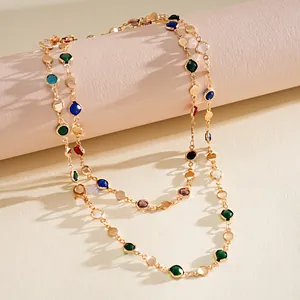 Detail view of colorful crystals and gold geometric disks on a long chain necklace
