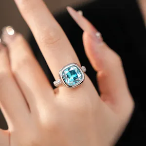 Primo piano di un anello elegante con zircone blu a cuscino e fascia in pavé.