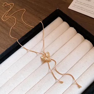 Detailed macro view of an elegant textured gold heart lariat necklace on a jewelry display tray