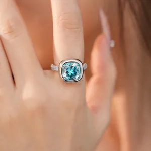 Vista dettagliata di un elegante anello d'argento con zircone azzurro quadrato al dito.