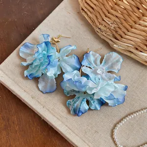Close-up detail of layered blue gradient fabric flower earrings with gold studs.