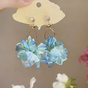 Detail showing textured light blue fabric petals of the floral earrings