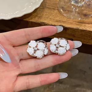 Elegant white rose cluster earrings with sparkling rhinestone accents on silver needle studs