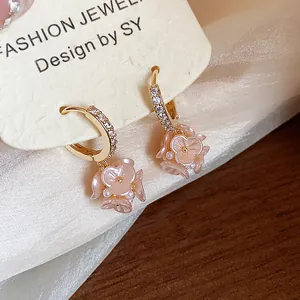 Close-up of elegant gold hoop earrings with zircon stones and pink flower charms