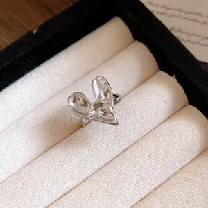 Macro view of a silver heart-shaped ring with unique liquid metal texture in a jewelry box.