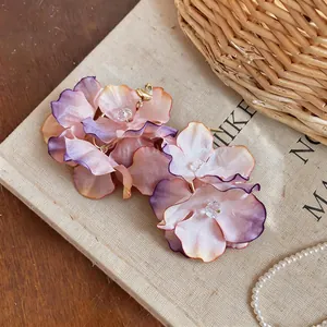 Close-up detail of purple and peach fabric flower earrings on a textured book