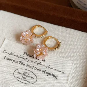 Close-up of elegant French style hoop earrings with pink flower and pearl charms.