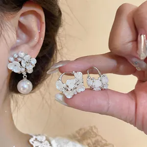Close-up of elegant white floral earrings with large pearl drop and rhinestones
