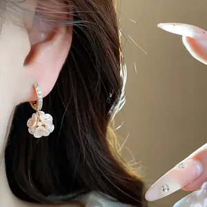 Detailed close-up of zircon flower hoop earrings with pearlescent petals and pearls.