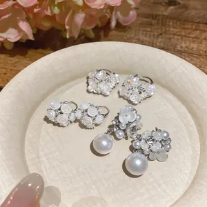 Elegant white floral and pearl earring set with delicate rhinestone details and silver posts