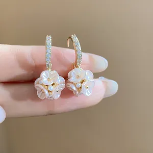 Close-up detail of French style zircon gold hoop earrings with pearl flower ball